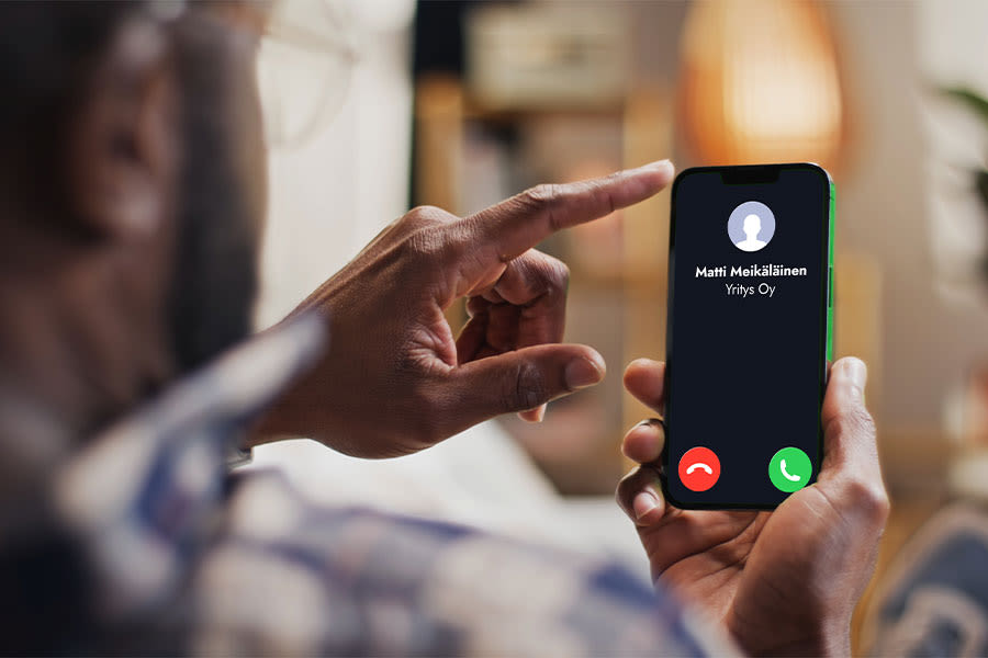 puhelimen näyttö, jossa saapuva puhelu ja teksti "Matti Meikäläinen, yritys Oy"