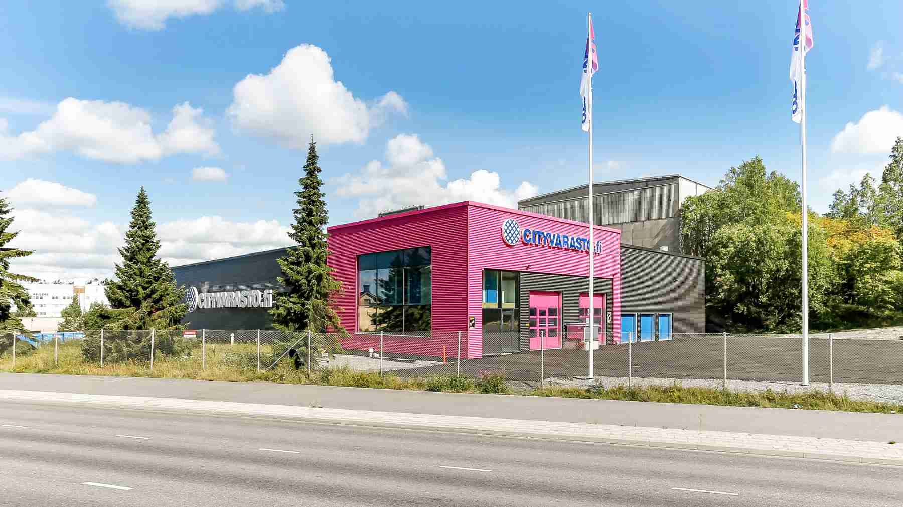 Cityvaraston varastorakennus ulkopuolelta, pinkki sisäänkäynti ja Cityvarasto-logo rakennuksen julkisivussa