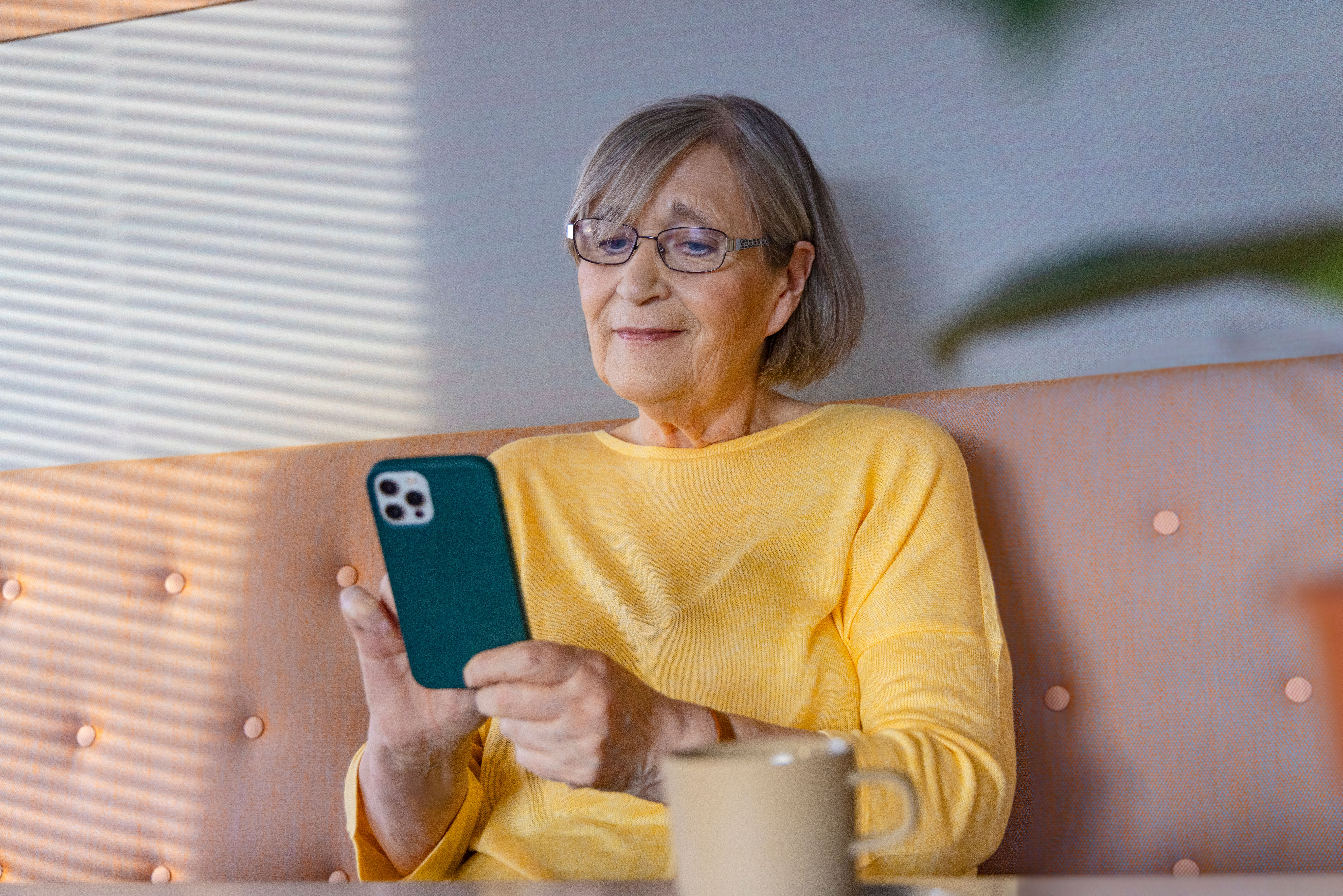 Senior woman sitting on the sofa watching her smartphone