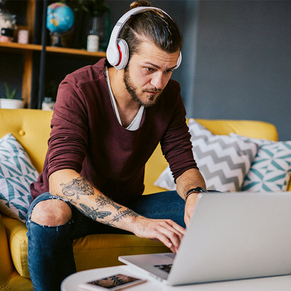 Man using laptop and listening to headphones