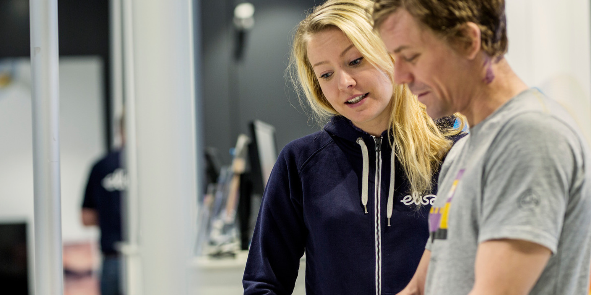 myyjä esittelee puhelinta asiakkaalle Elisan myymälässä