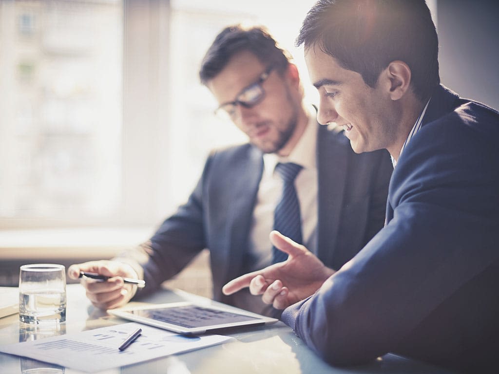 Elisalta saat Private Networks eli privaattiverkon luotettavasti ja sujuvasti. Kaksi miestä istuu pöydän ääressä selaten presentaatiota tabletilta.