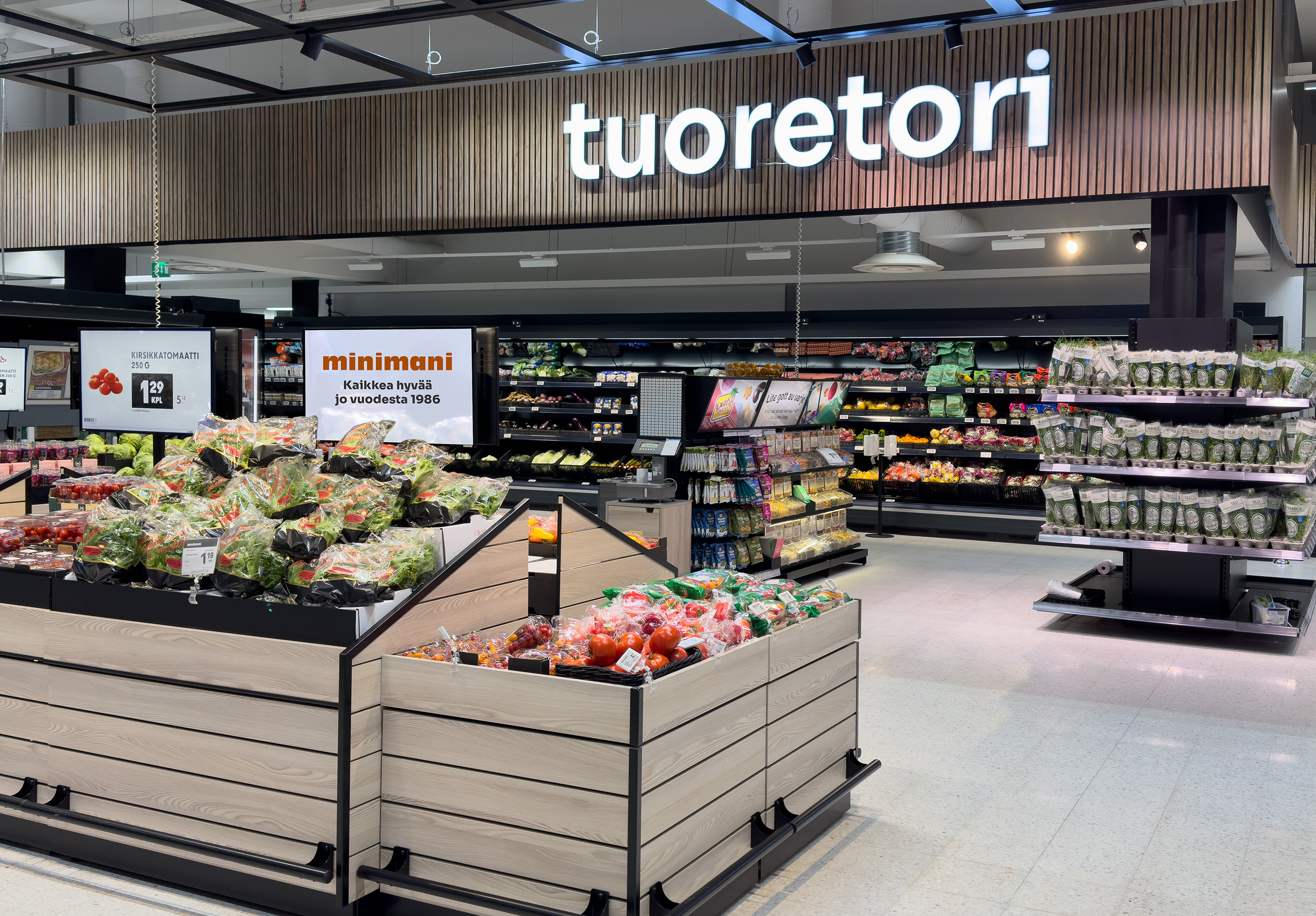 Retail produce aisle with a Minimani promotional sign, highlighting the operational environment whose reliability was strengthened through IT and cybersecurity modernization by Elisa.