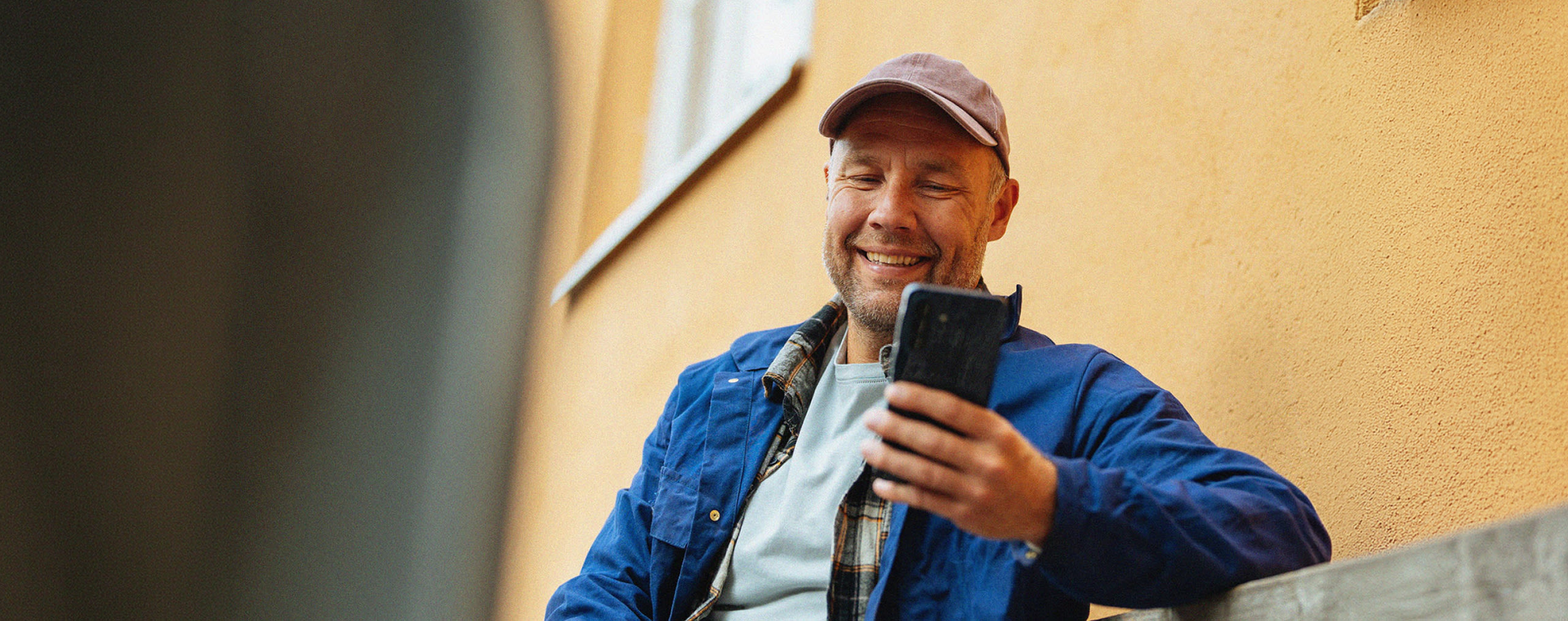 Mies on kerrostalon pihalla puhelin kädessään
