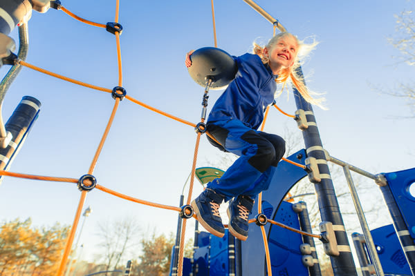 siniasuinen tyttö pallon kanssa kiipeilytelineessä