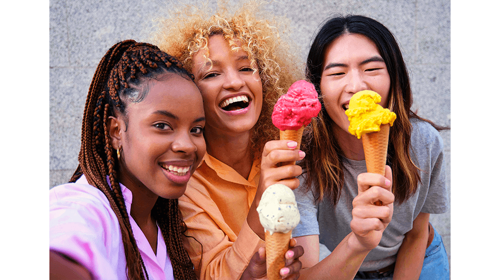 Kolme naista jäätelöt kädessä poseeraamassa kameralle
