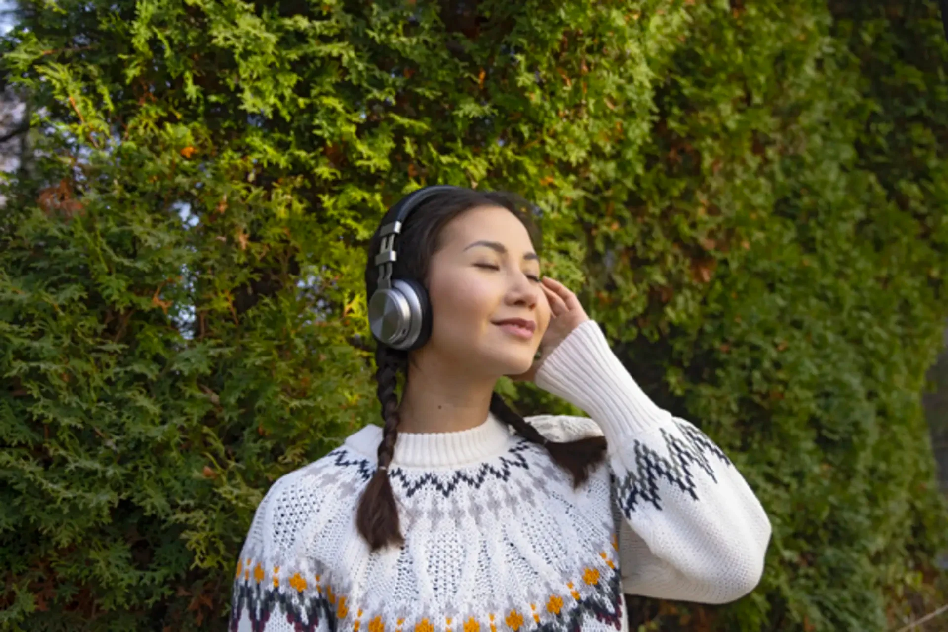 nainen kuuntelee musiikkia kuulokkeistaan ulkona