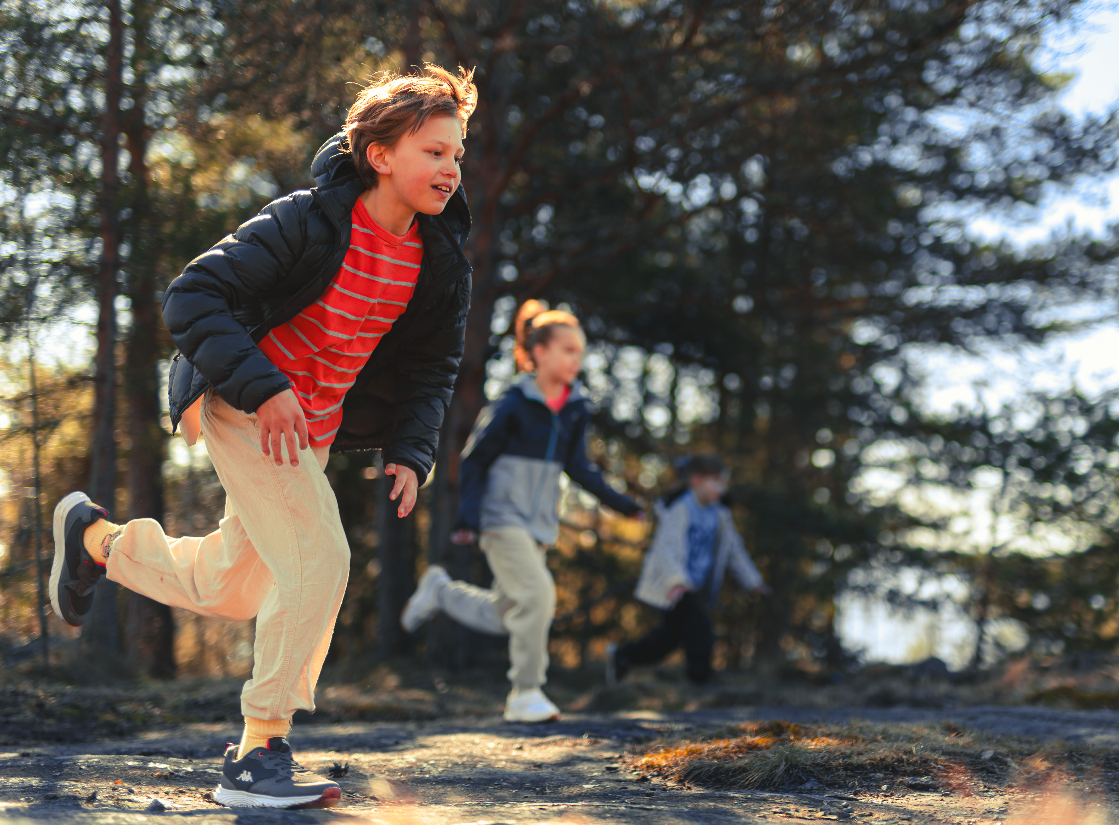 kolme lasta juoksee innoissaan ulkona