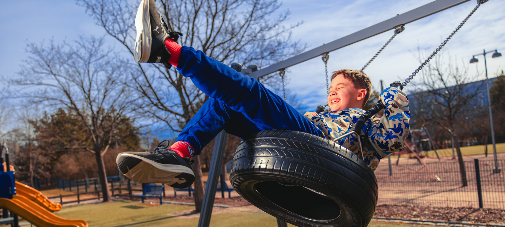 poika keinuu kovaa vauhtia leikkipuiston rengaskeinussa