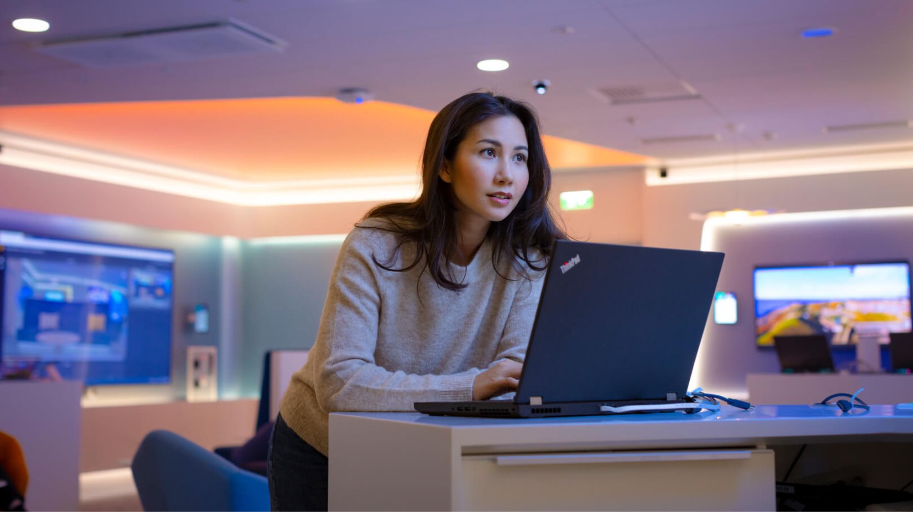 Nainen seisoo kannettavan tietokoneen edessä toimistoympäristössä. Tiedote Elisa jatkaa Vmware-kumppanina.