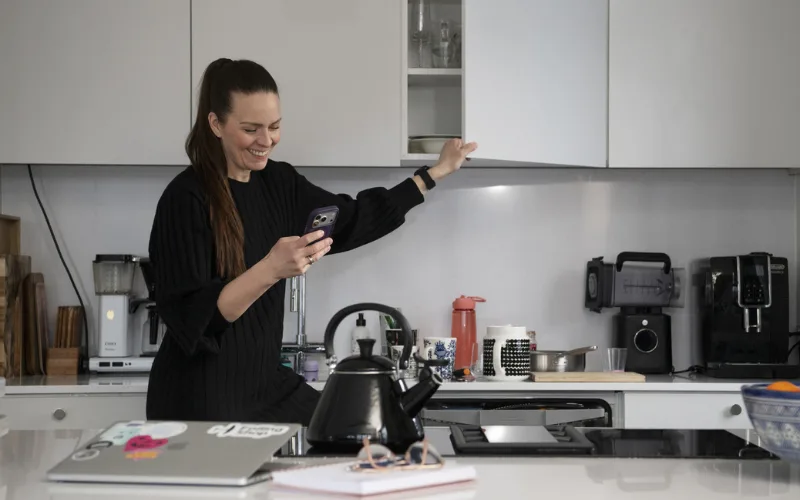 Hanne Kettunen keittiössä puhelin kädessä
