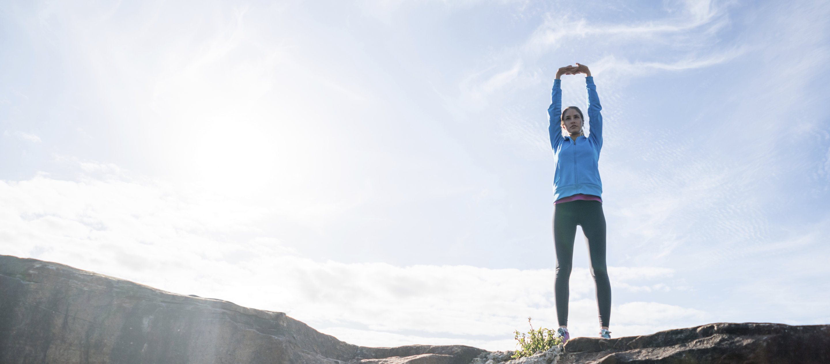 Nainen venyttelee ulkona lenkkeillessään.