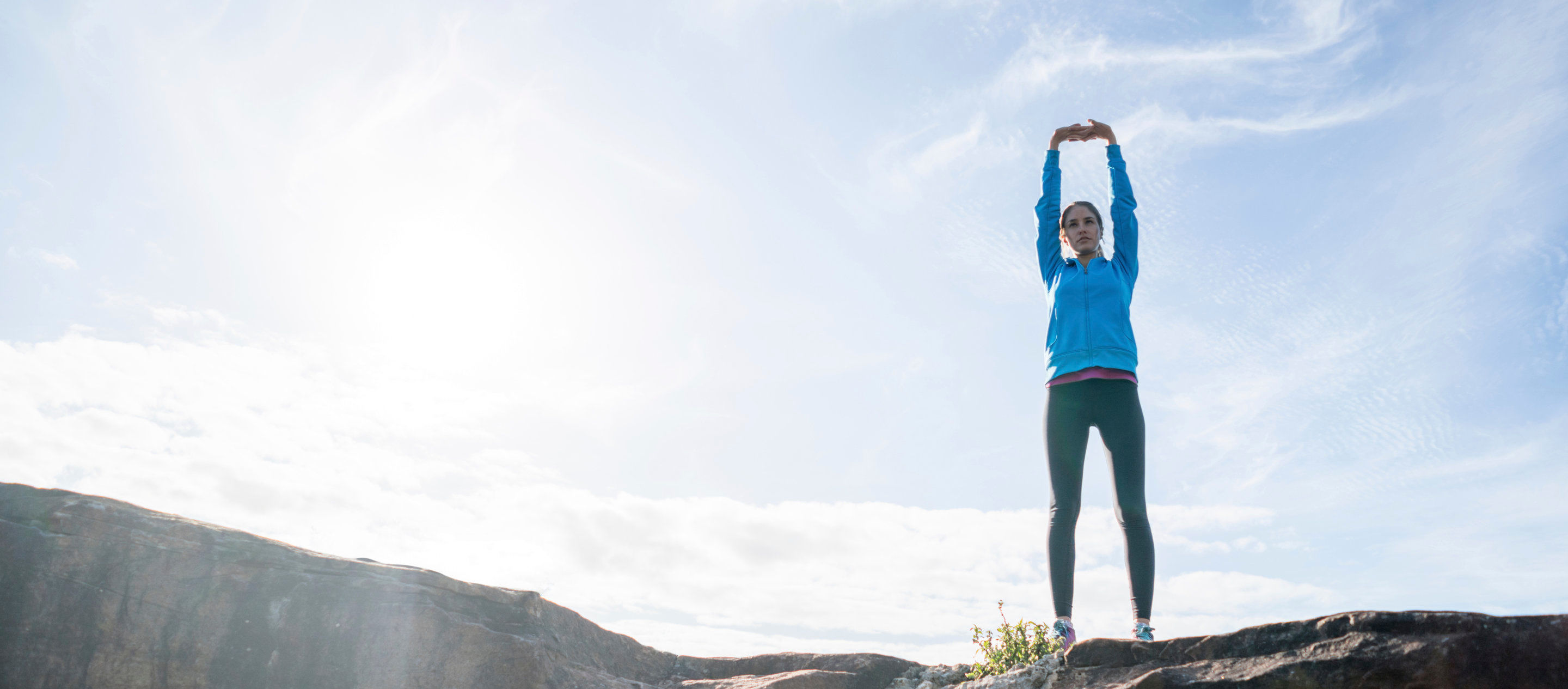 Nainen venyttelee ulkona lenkkeillessään.