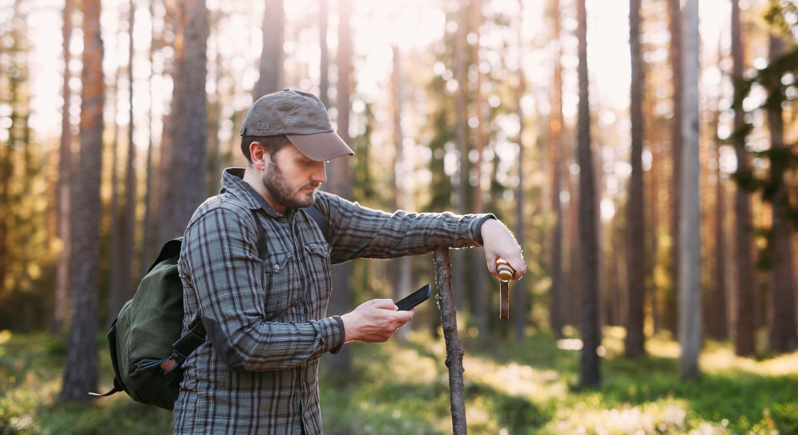 Mies kännykällä metsässä.
