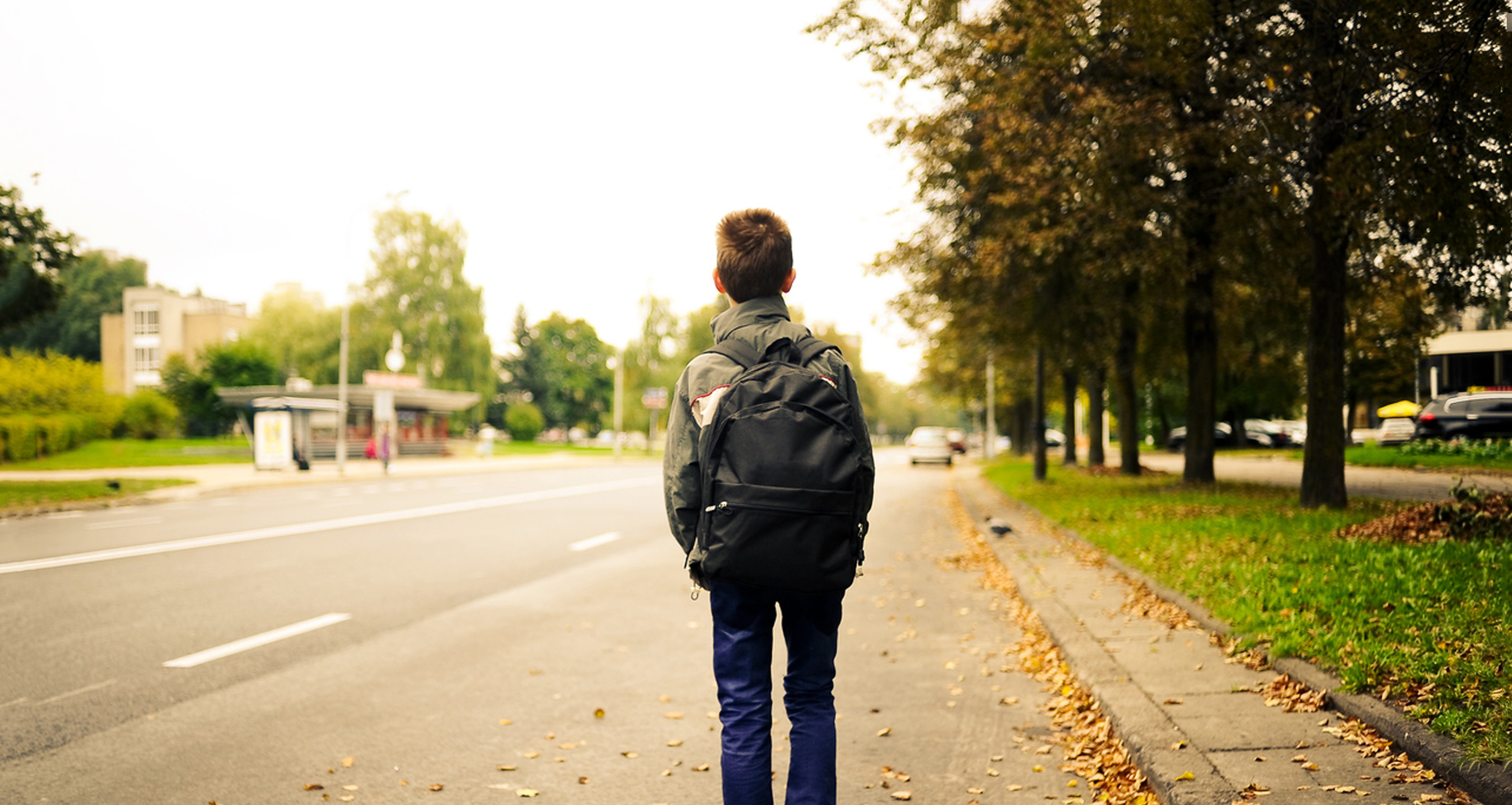 Lapsi seisoo reppu selässä tien varressa.