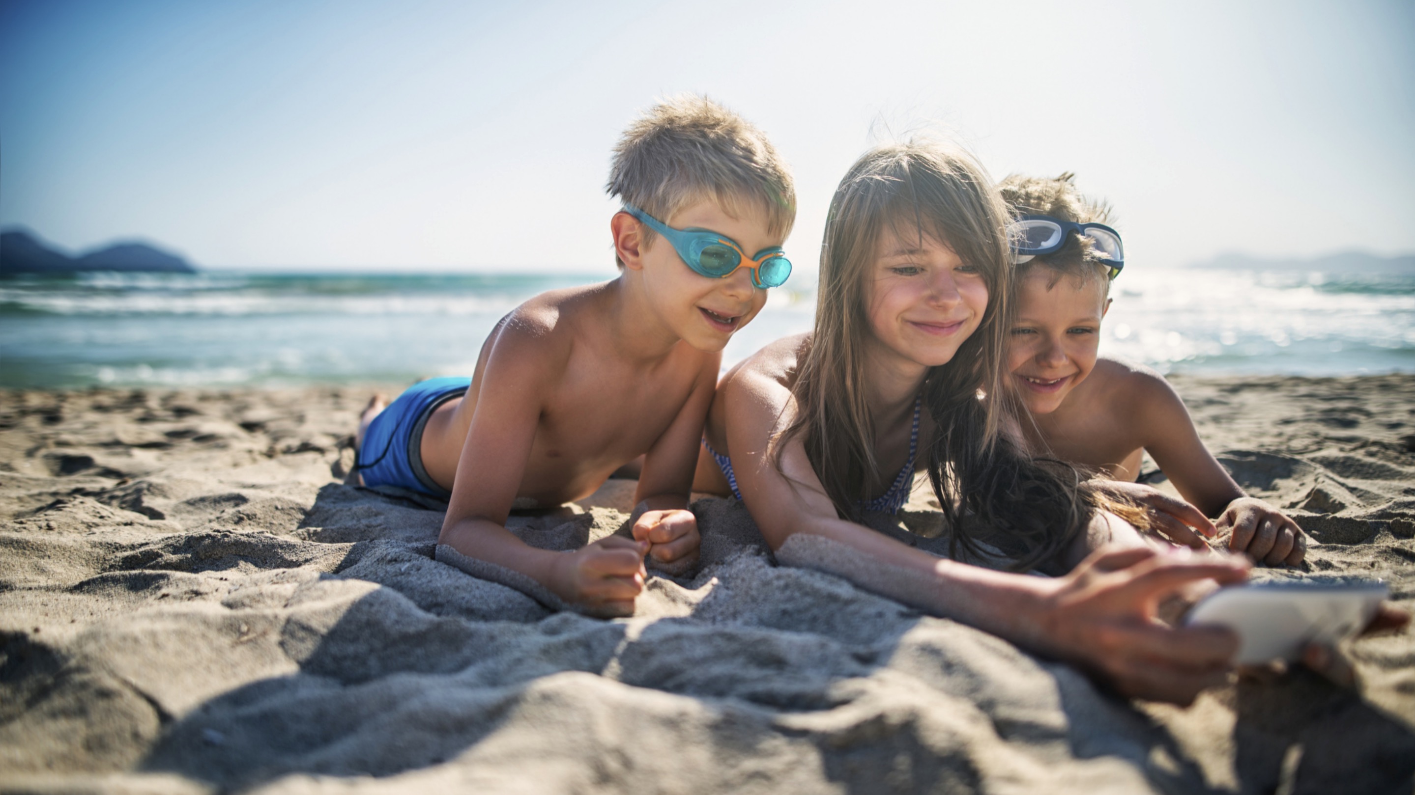 Lapset ja puhelin rannalla.