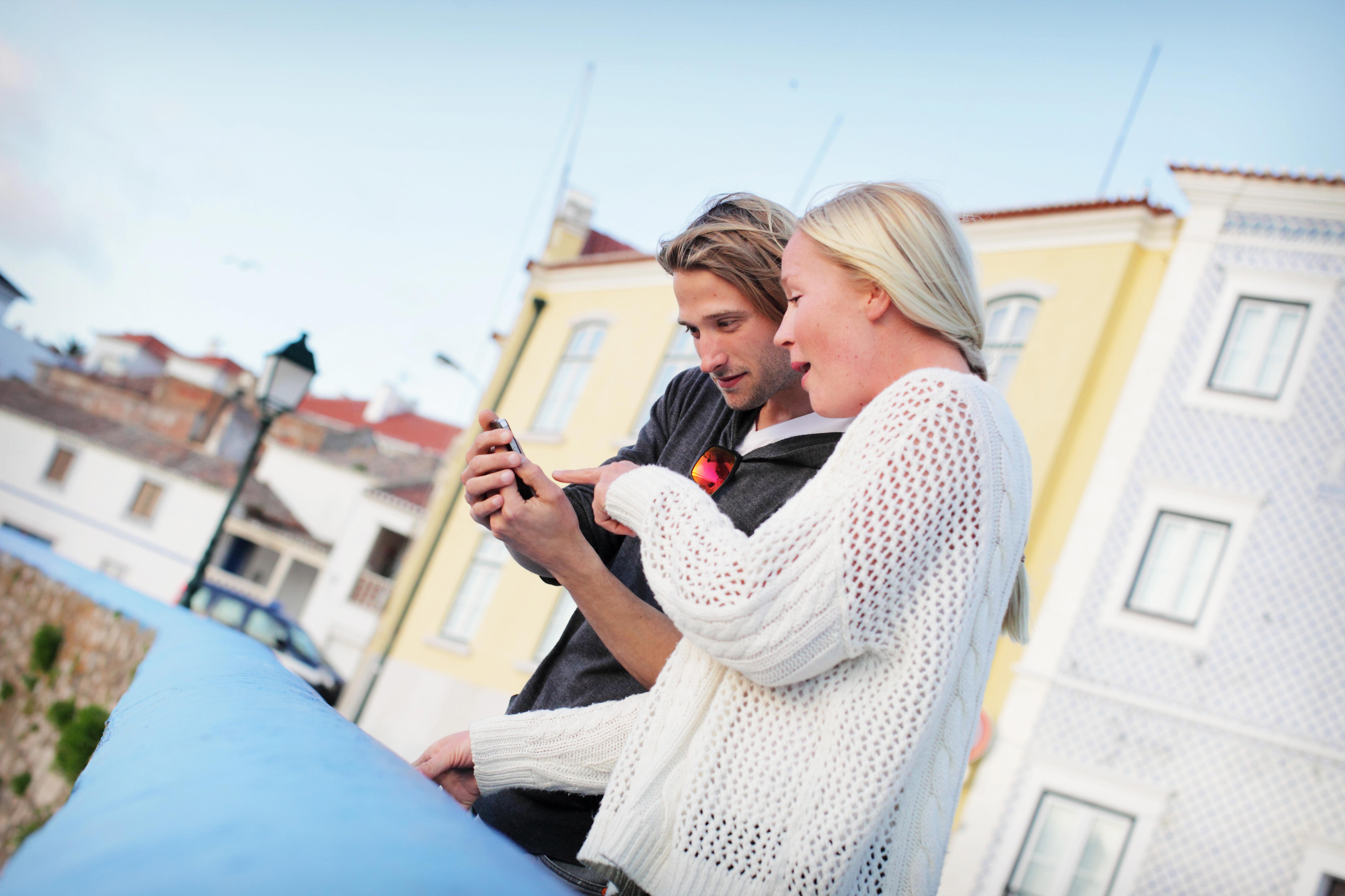 Mies ja nainen kaupungilla selaamassa puhelinta