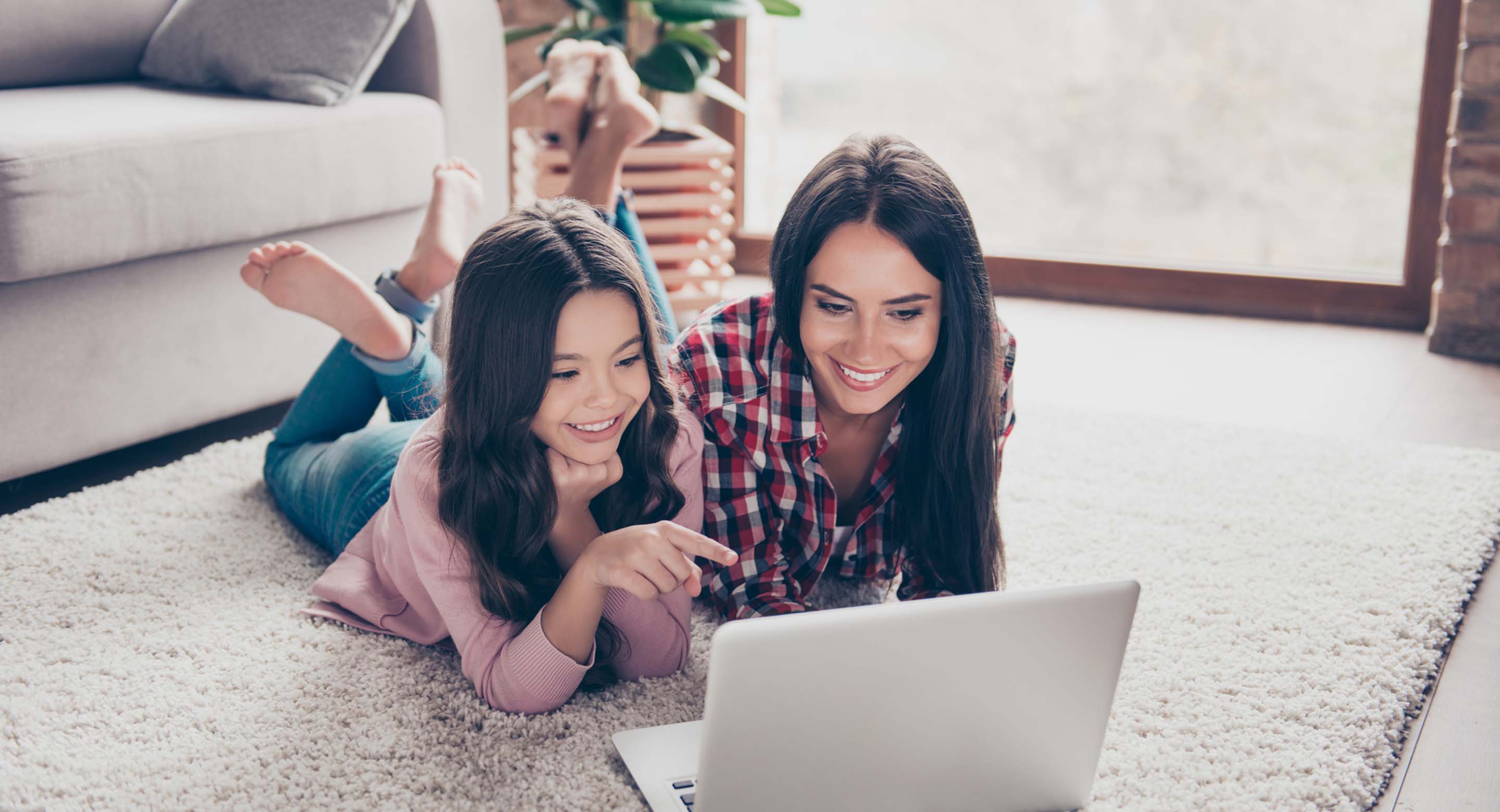 äiti ja tytär makoilevat olohuoneen lattialla läppärin edessä ja katsovat yhdessä ruudulta jotakin