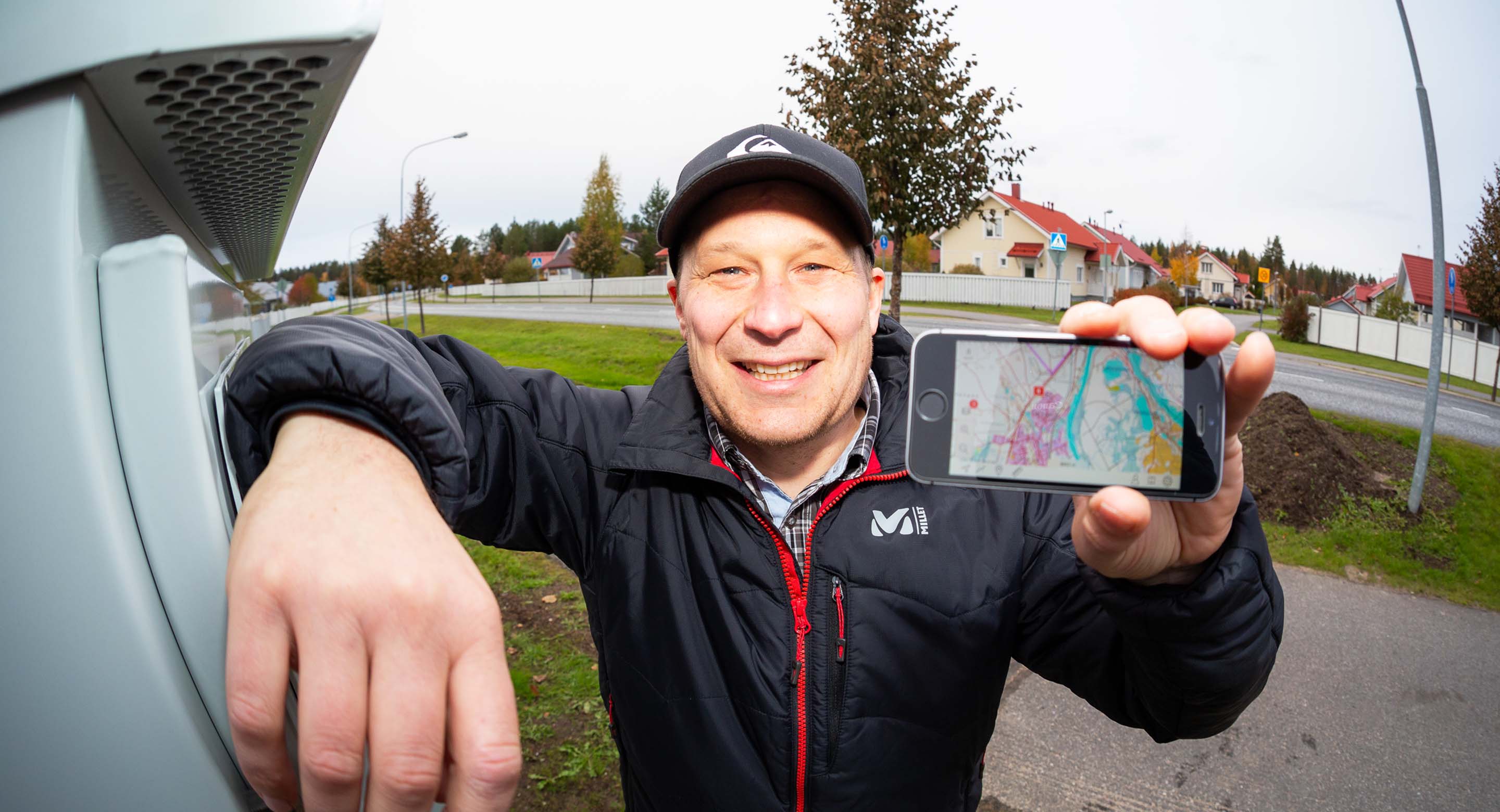 Perheen isä esittelee nopeaa kuituyhteyttään omakotitalon pihalla