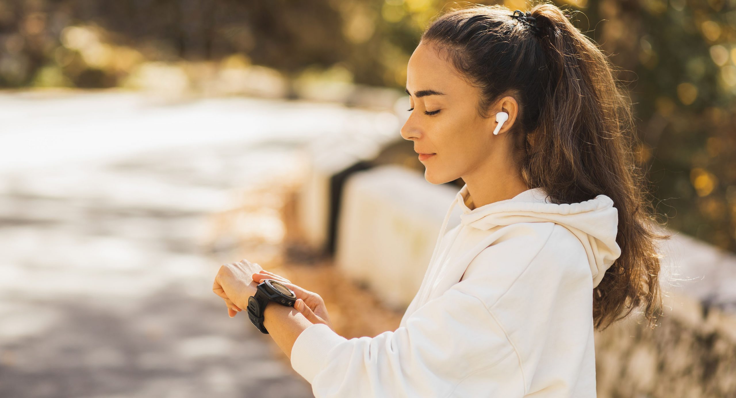 Nuori nainen katsoo ranteessa olevaa älykelloa kuulokkeet korvissa. Lenkille ei tarvitse ottaa puhelinta mukaan, kun puhelut tulevat älykelloon