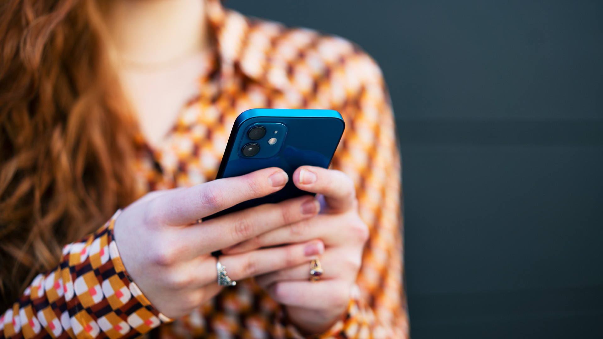 Elisa Mobiilivarmenteen käyttöä havainnollistava kuva, jossa nainen on älypuhelin kädessään.