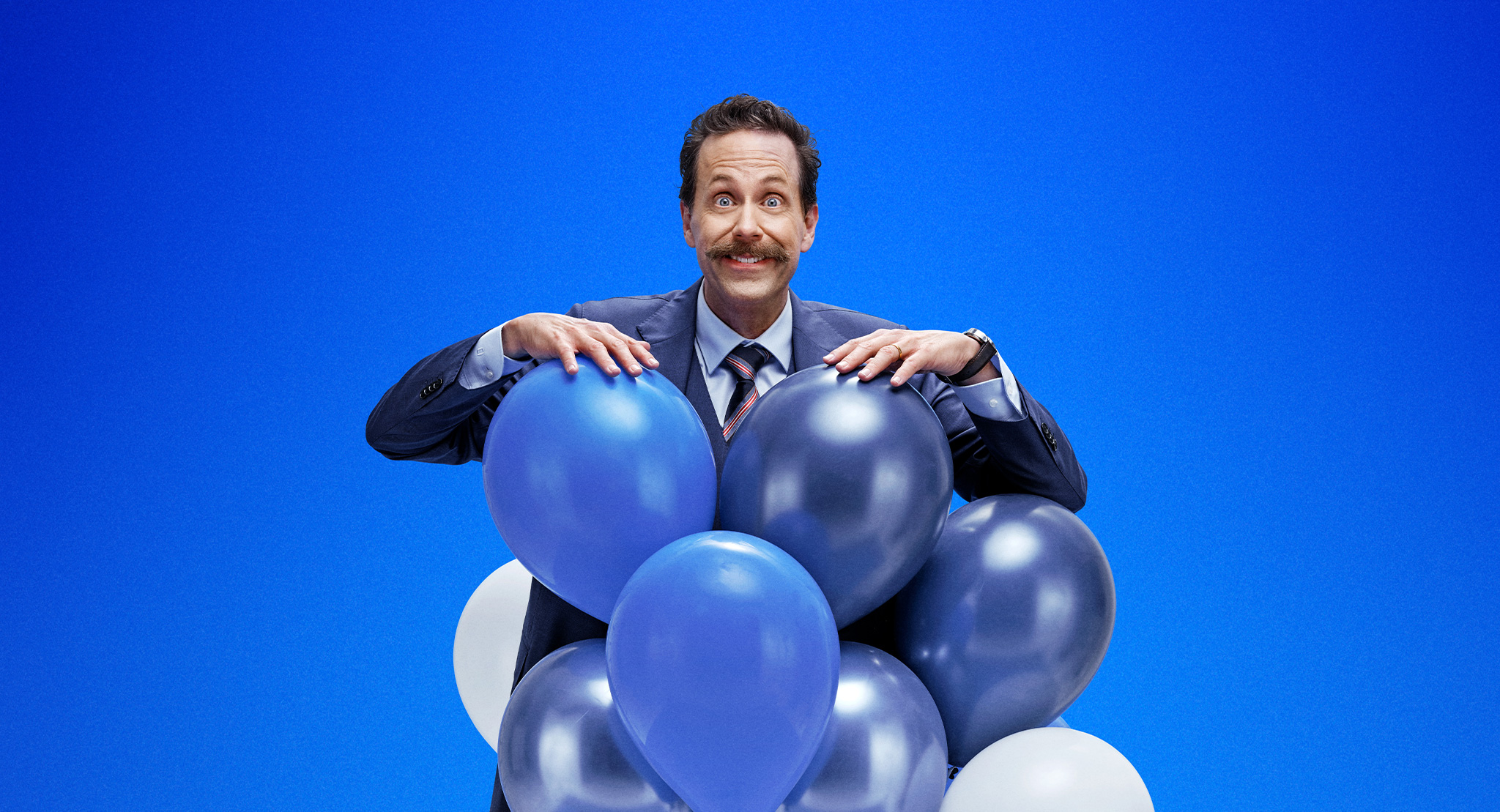 Elisa Etuohjelma - hymyilevä mies sinivalkoisten ilmapallojen kanssa.