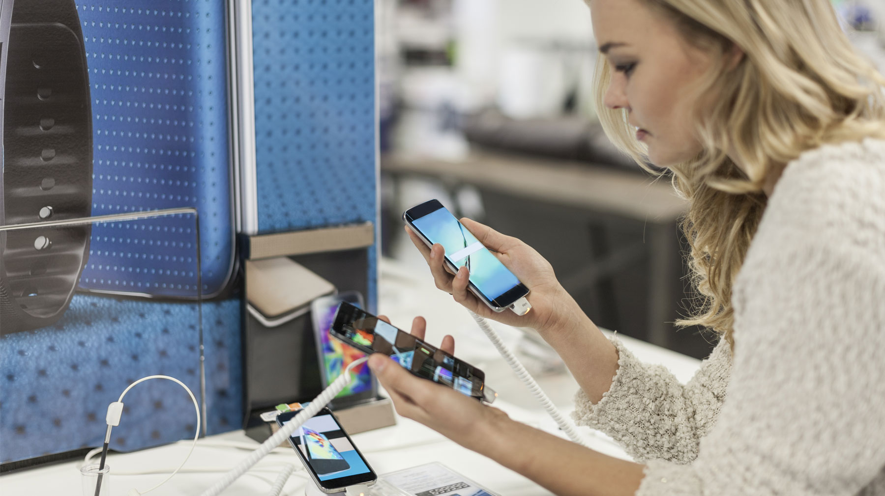 Puhelimen valinta yritykselle. Nainen tutkii erilaisia puhelimia.