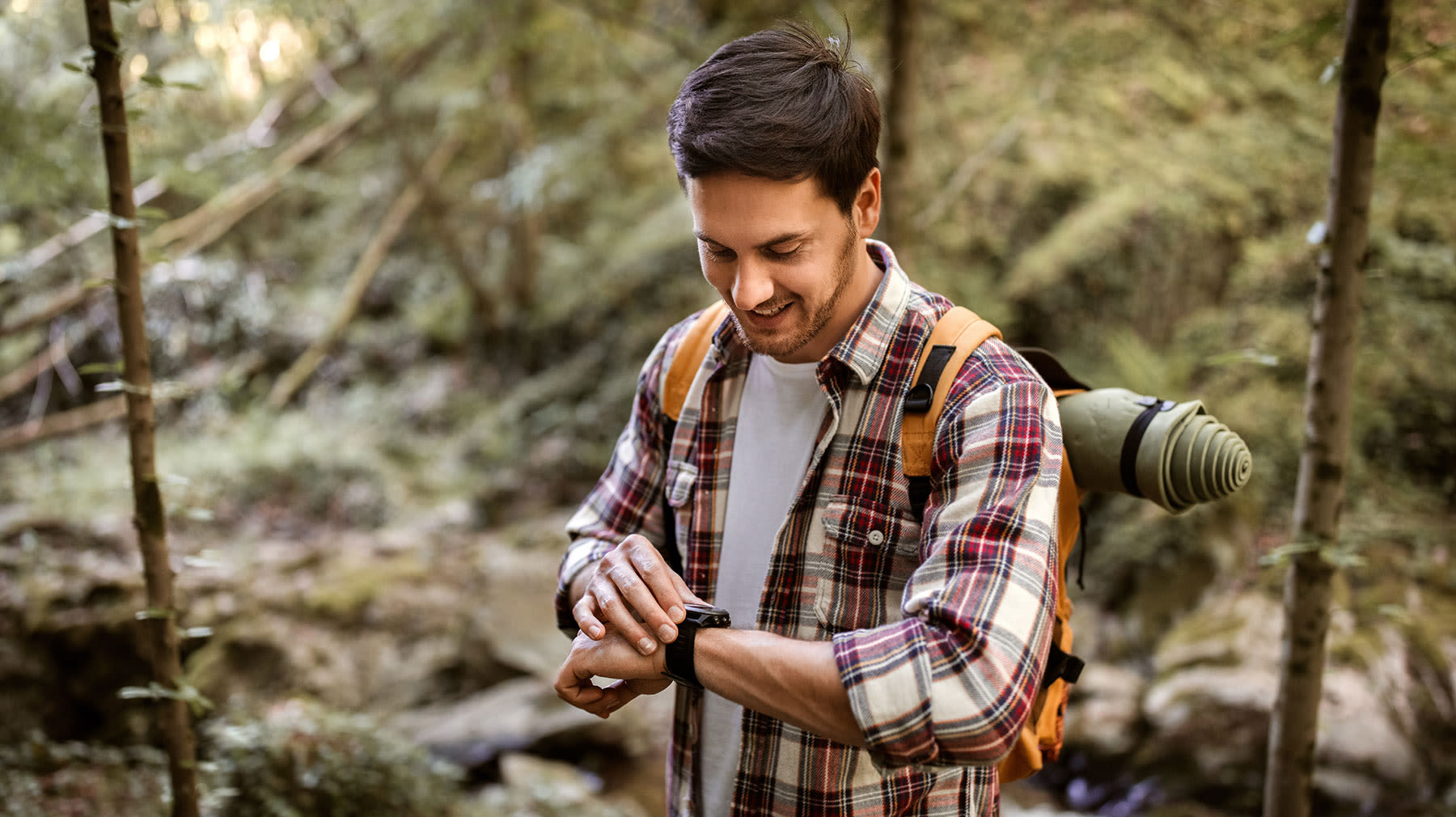 Mies katsoo metsässä aktiivisuusrannekettaan.