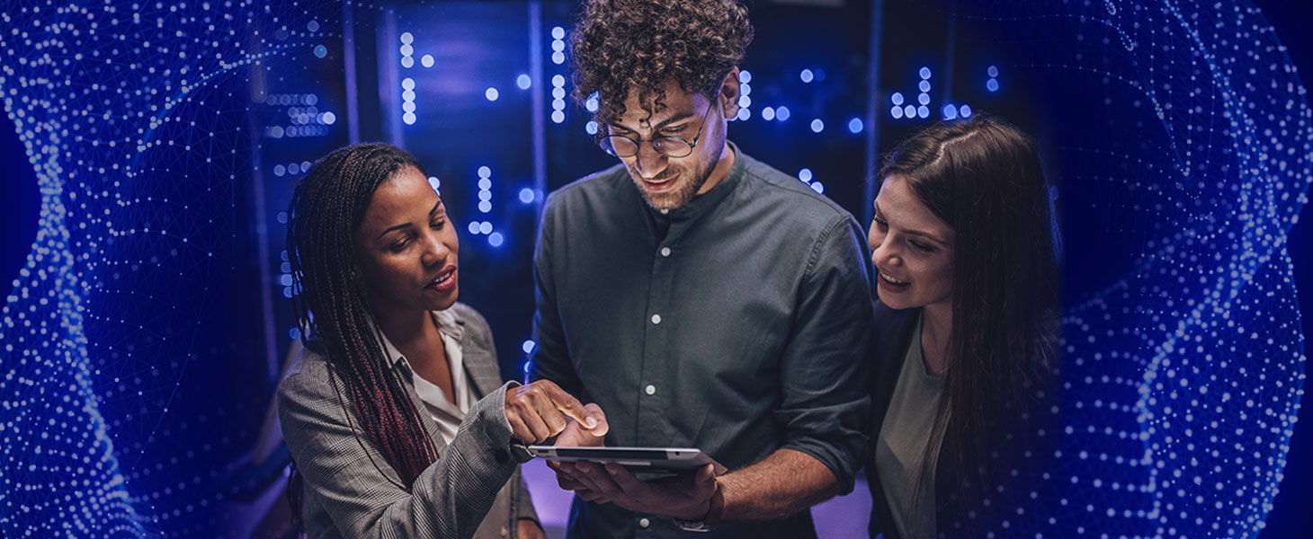 Sinisävyinen kuva, jossa kaksi naista ja mies katsovat yhdessä tabletin ruutua. Kuva visualisoi kyberturva-alan ammattilaisia eli kyberintekijöitä.