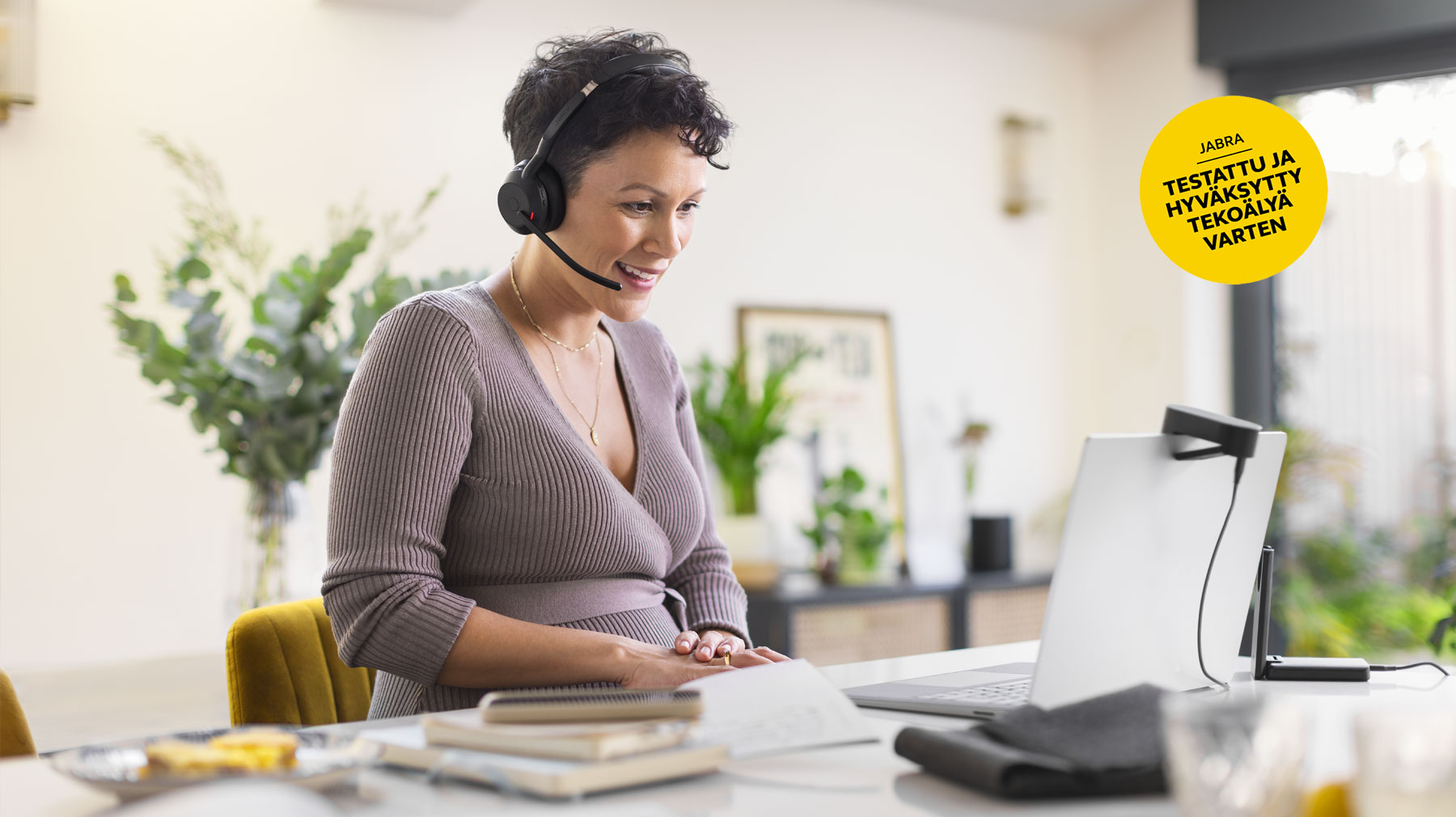 Nainen työskentelee tietokoneella kuulokkeet päässään