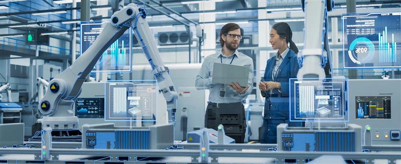 Webinaarin kuvituskuva, jossa kaksi miesti keskustelevat tehtaassa. Toisella miehellä on läppäri kädessä.