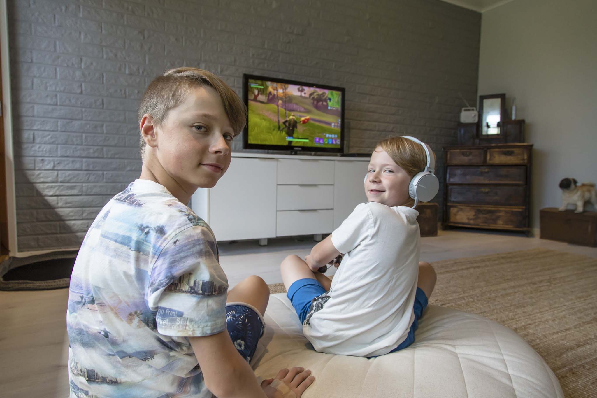 Kaksi nuorta poikaa pelaamassa konsolipelejä television ääressä