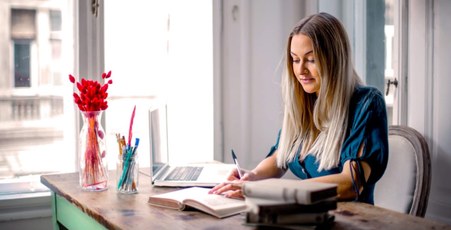 Nainen kirjoittaa kynällä vihkoon