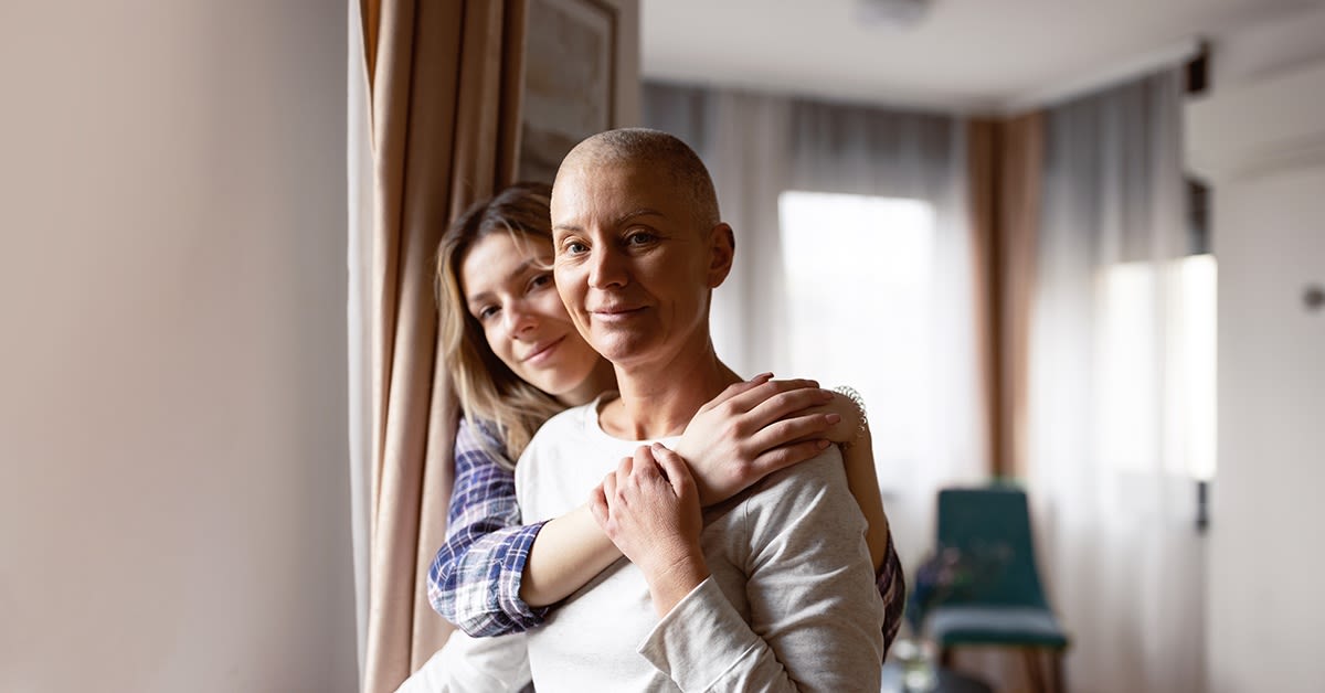 ICT-ratkaisut terveydenhuollolle. Nainen halaa sairaalahuoneessa istuvaa naista.