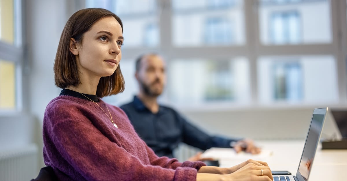 Solutions Partner for Microsoft Cloud. Nainen työskentelee kannettavalla tietokoneella ja katsoo ylöspäin.