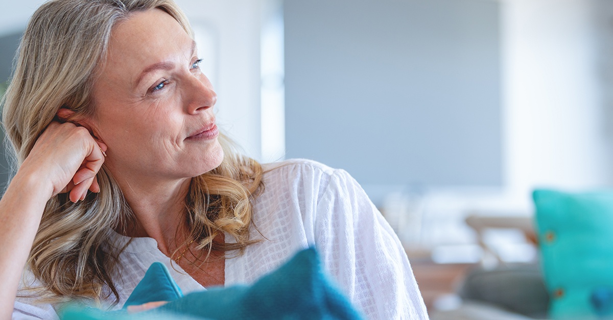 Terveyspalvelut kotiin. Nainen istuu kotisohvalla ja hymyilee.