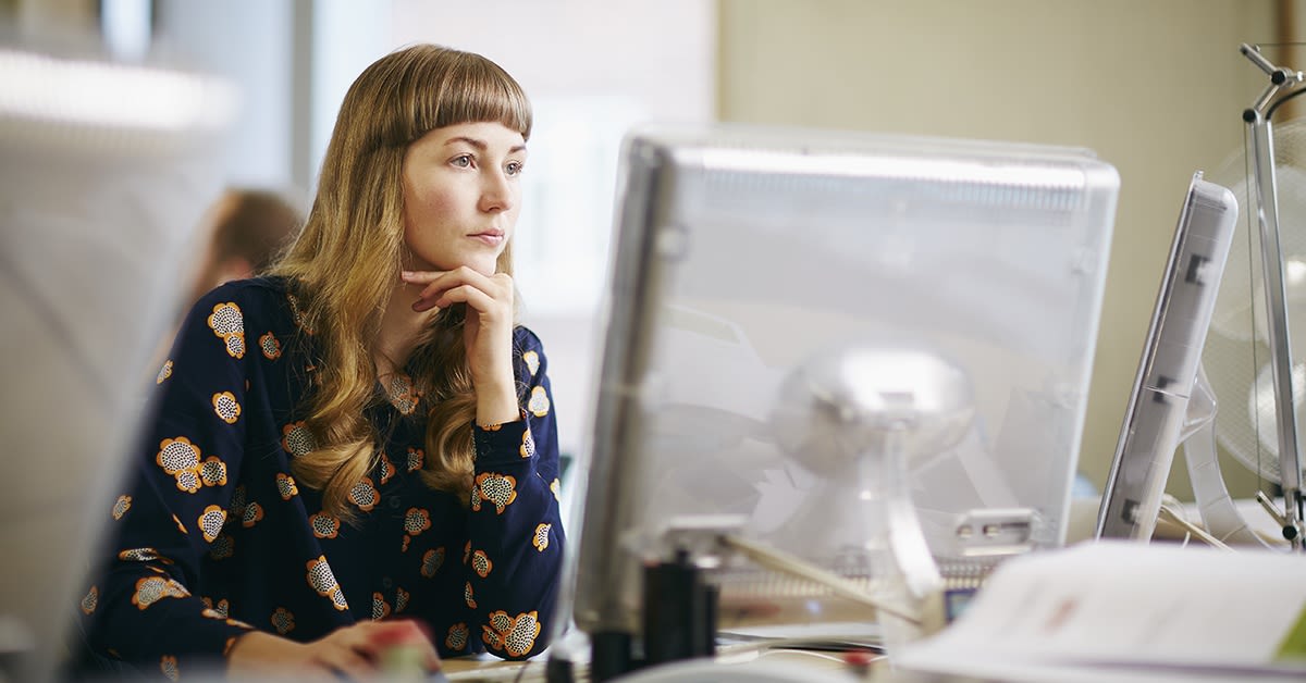 Nainen työskentelee pöytäkoneella keskittyneesti. Elisan hybridipilvi.