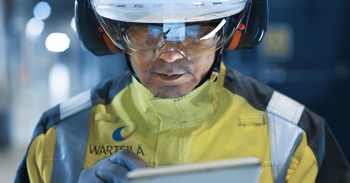 Mies työskentelee tehtaalla tabletti kädessään. Wärtsilä varautuu kyberuhkiin.