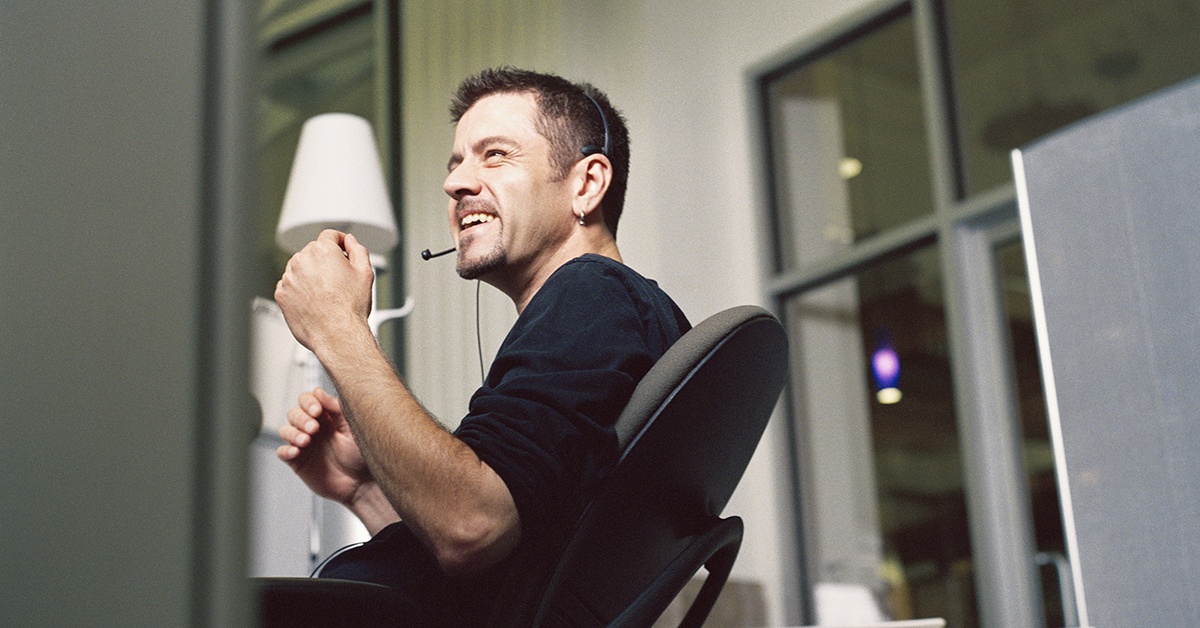 Mies istuu toimistossa ja iloitsee onnistumisesta. Hybridipilvi auttaa liiketoiminnassa.