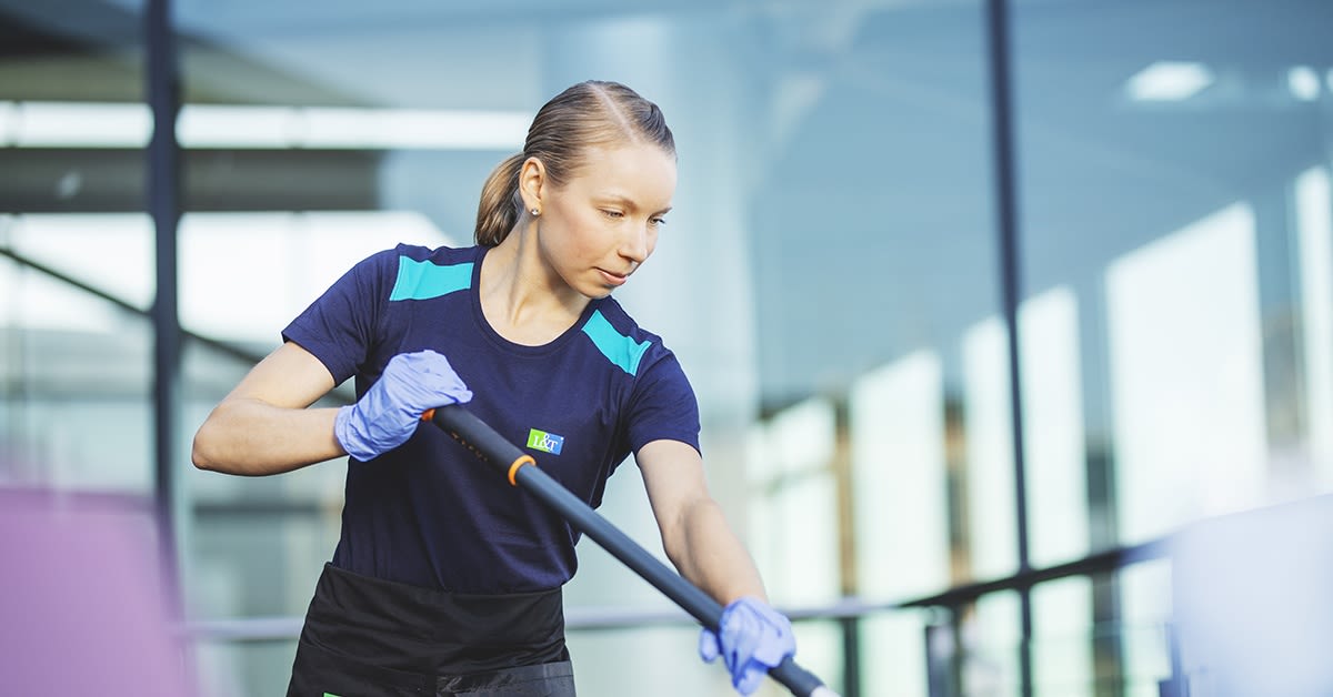 Nainen työskentelee siivoojana. Älypuhelin siivoojan työvälineenä.