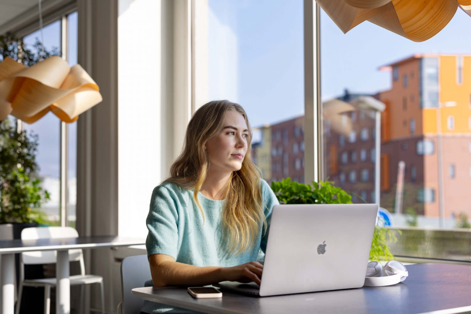 Nainen työskentelee tietokoneella ja katsoo ikkunasta ulos. Tekoäly mullistaa asioinnin.