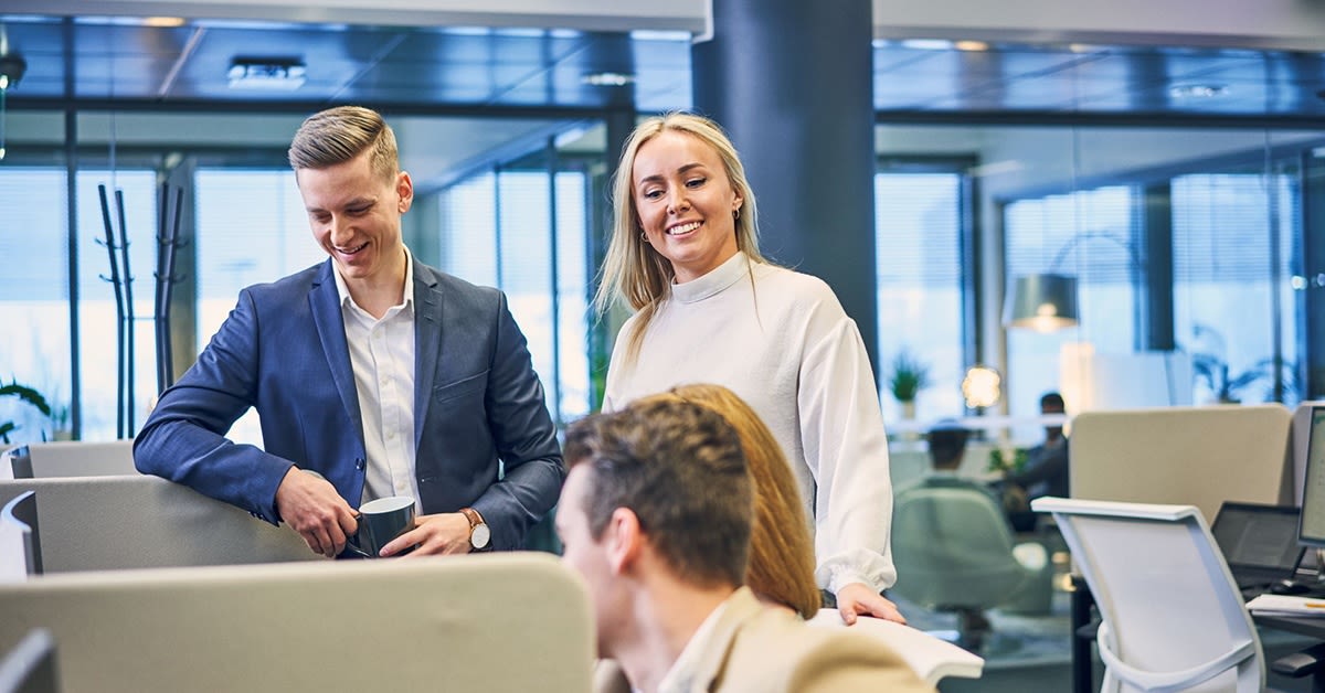 Hymyilevät nainen ja mies työskentelevät toimistolla. Azure-kumppani.