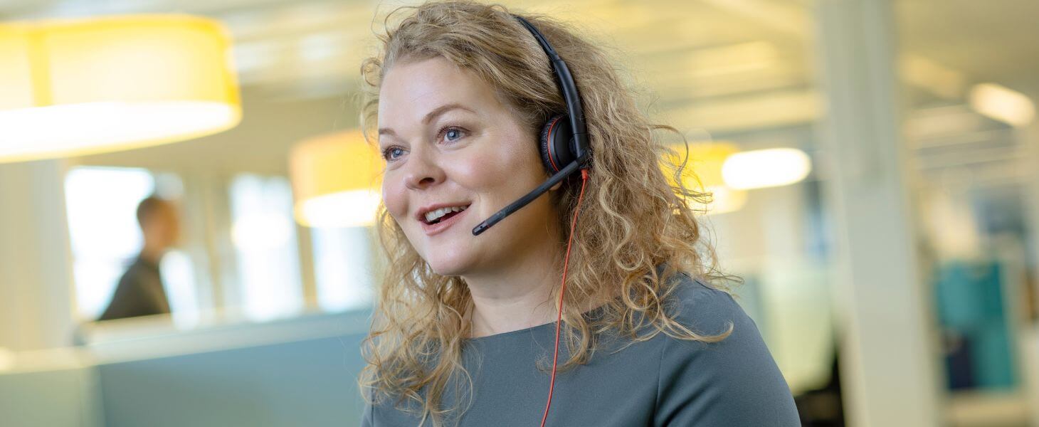 Hymyilevä nainen kuulokkeet päässä varmistaa, että asiakaspalvelussa onnistuminen tekoälyn avulla auttaa asiakkaita.