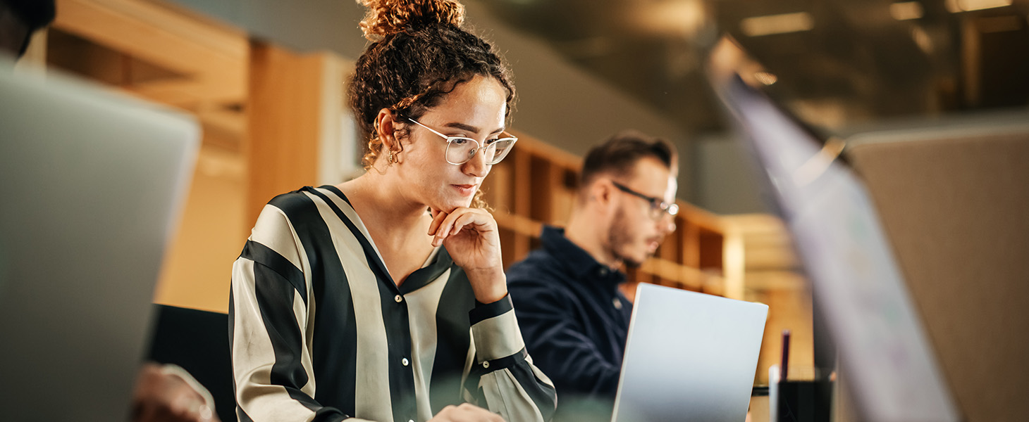 Nainen ja mies omien tietokoneidensa äärellä työskentelemässä. Kuvituskuva.