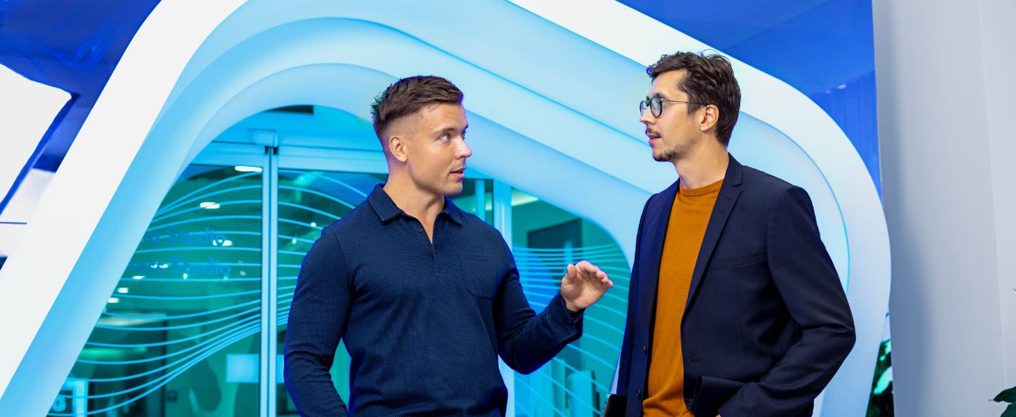 Kaksi miestä keskustelevat sinisen taustan edessä digi- ja tuottavuusloikassa onnistumisesta.