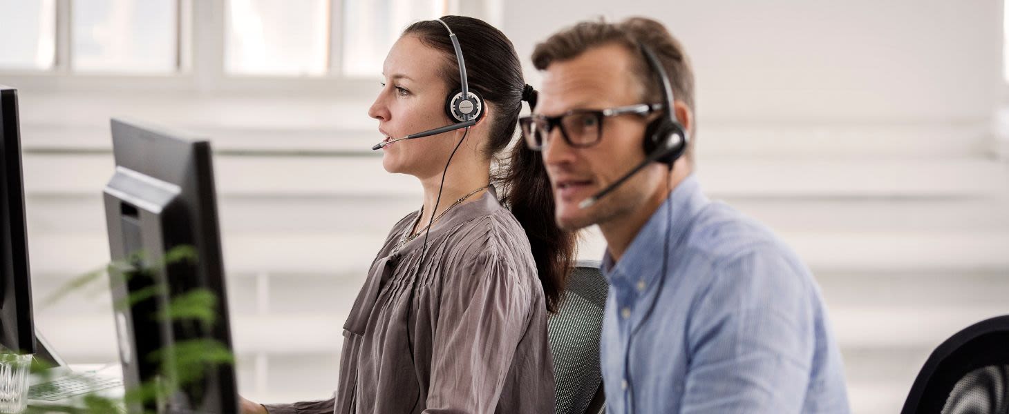 Mies ja nainen istuvat vierekkäin kuulokkeet päässä ja tietävät, miten tekoälyratkaisut asiakaspalvelussa tekevät arjessa sujuvampaa.