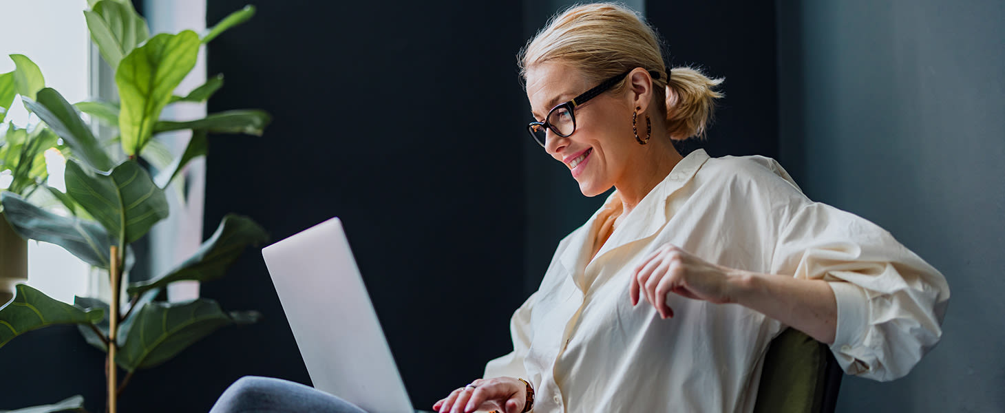 Webinaarin kuvituskuva, jossa vaaleahiuksinen nainen istuu rennosti tuolilla tietokone sylissään.