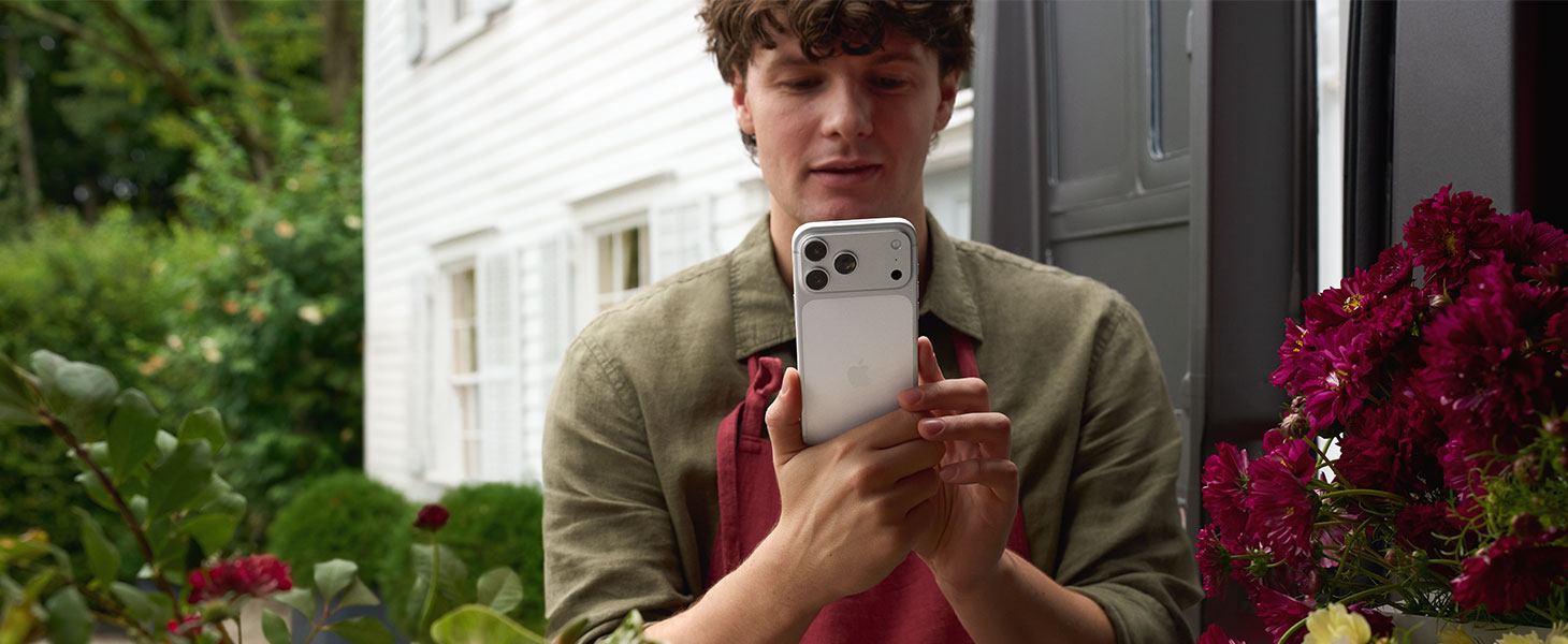 Kukkakauppias ottaa kuvaa iPhone 17 Pro -puhelimella.